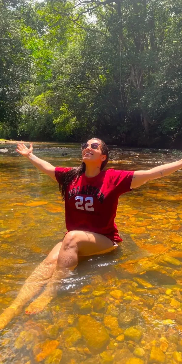 Lorene Patigra sorrindo na natureza, dentro do rio, representando sua essência leve por trás do trabalho.